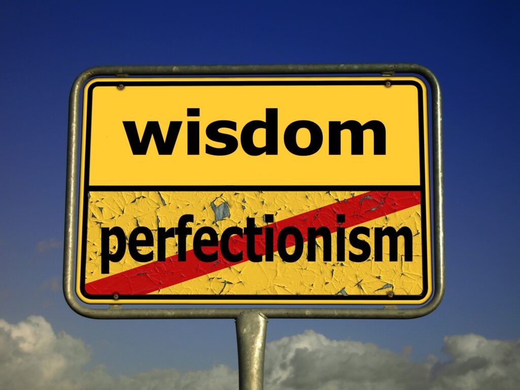 Sign with perfectionism crossed out and wisdom above it