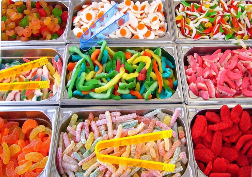 a collection of different kinds of gummy candies in bins.