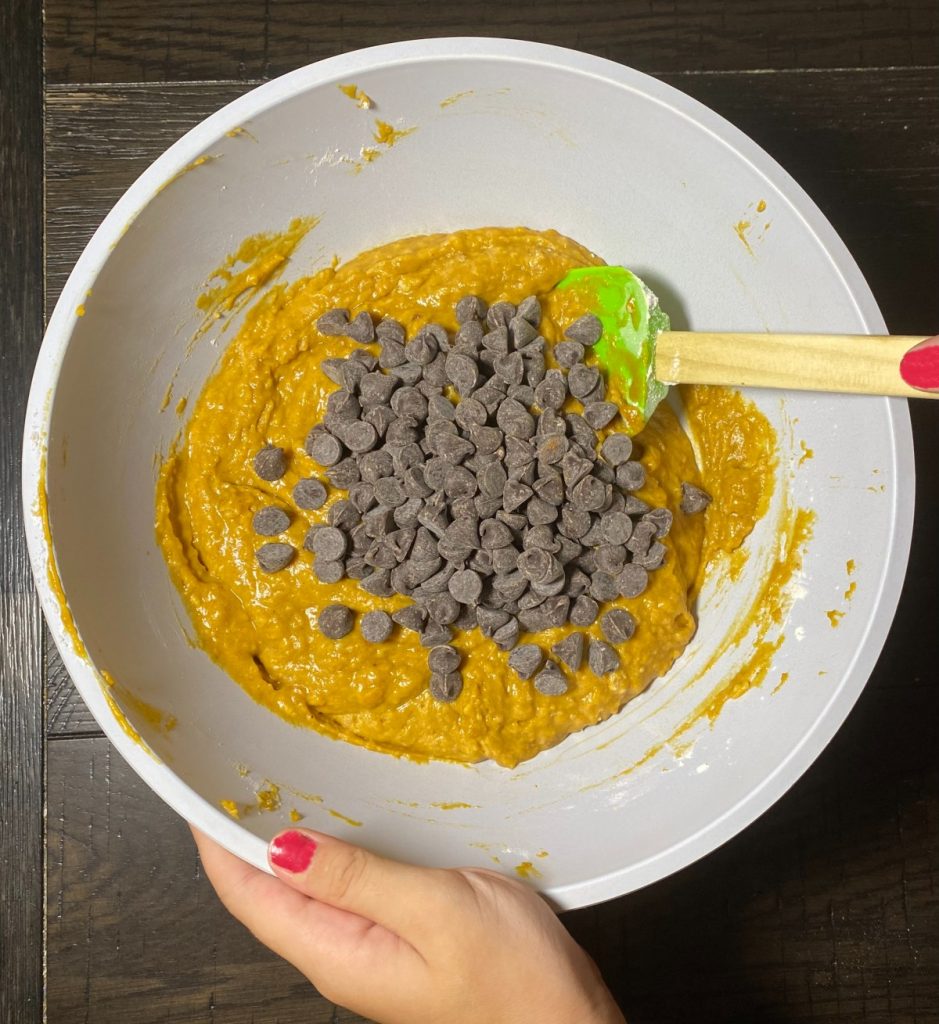 pumpkin muffin batter in a bowl with chocolate chips on top.