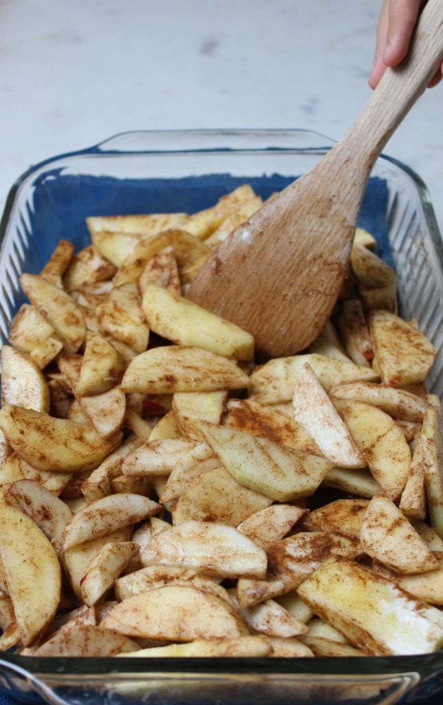 apple slices being spread in baking dish.