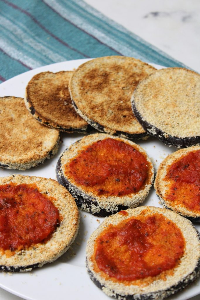 baked breaded eggplant on plate with tomato sauce.