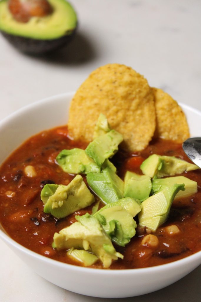 bowl of chili with avocado and tortilla chips.