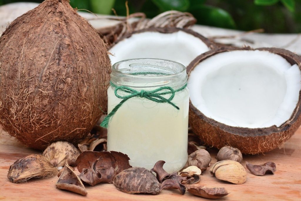 coconut oil in a jar with coconuts around it.