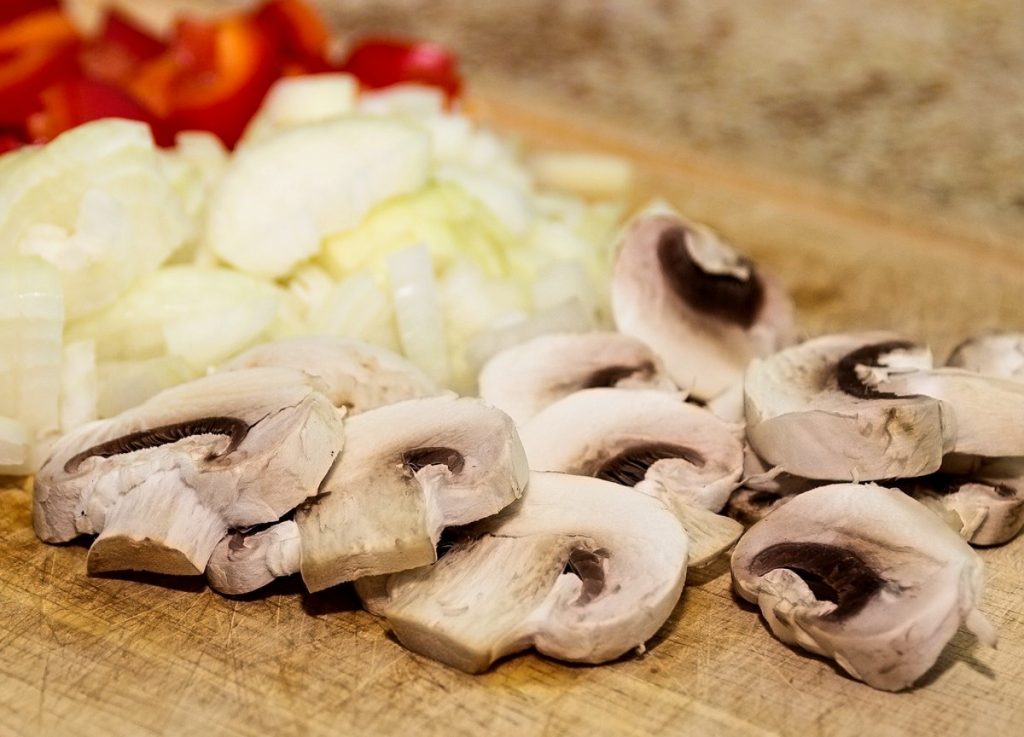 cutting board with sliced mushrooms and onions.