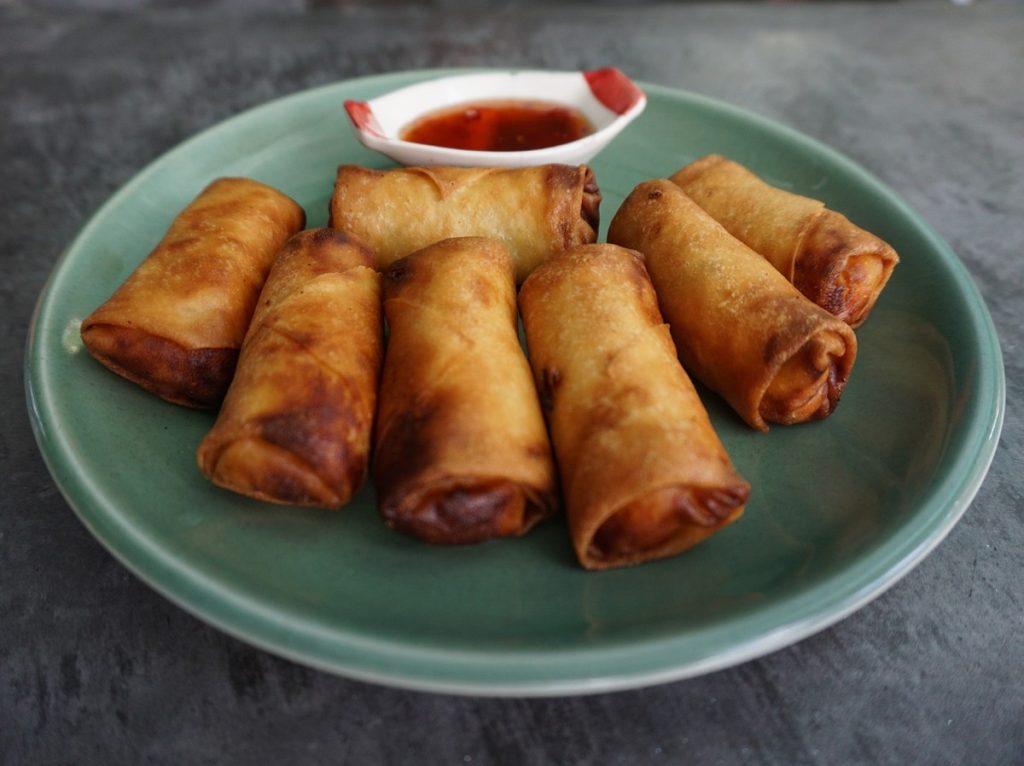 egg rolls on a plate with dipping sauce.
