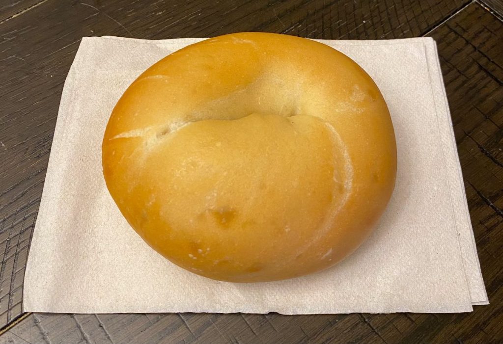 Plain bagel on a white napkin.