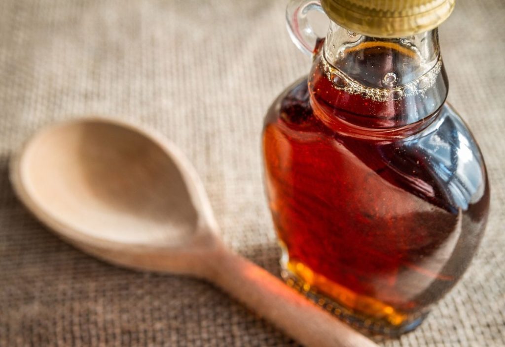 Bottle of maple syrup with a wooden spoon.
