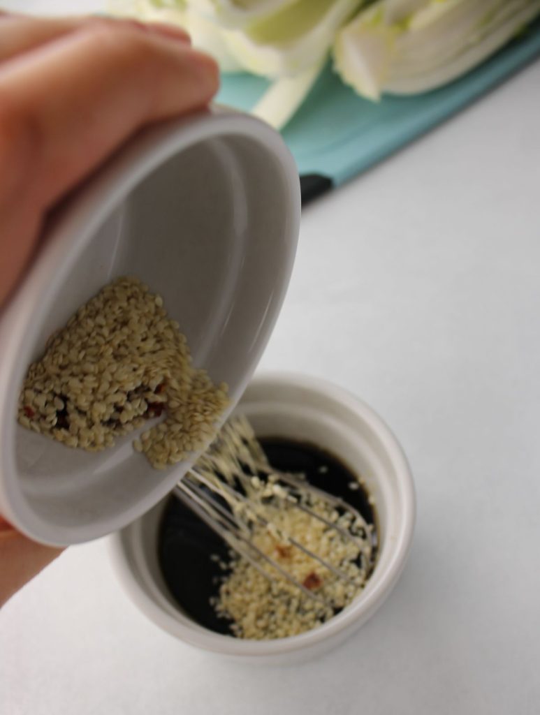 Sesame seeds being poured into sauce.