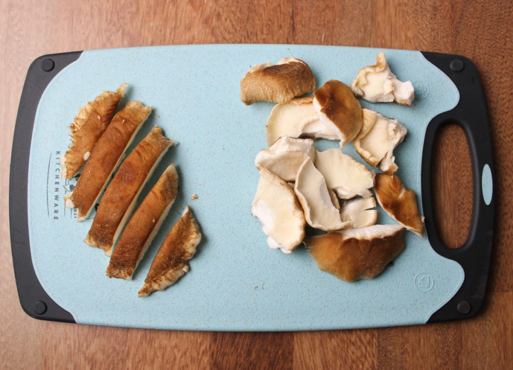 Shiitake mushrooms sliced and torn on a cuttingboard.