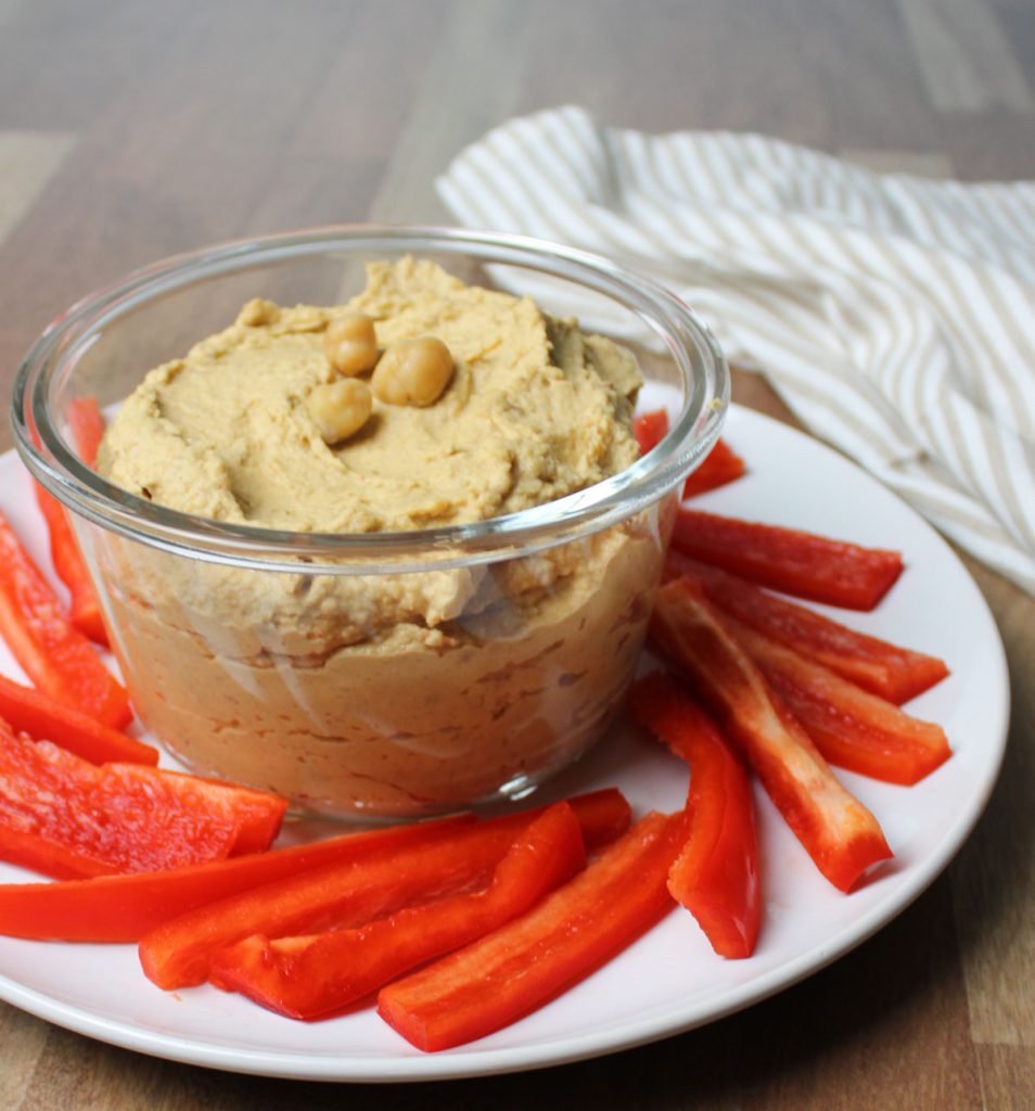Hummus on a plate with red pepper slices.