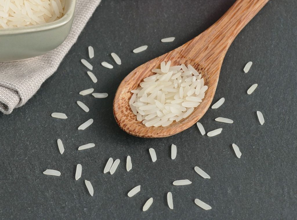 Wooden spoon with rice grains on it.