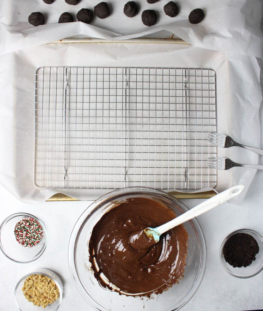 Bowl of melted chocolate with wire rack and toppings.