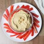 Bowl of eggplant hummus with red pepper slices.