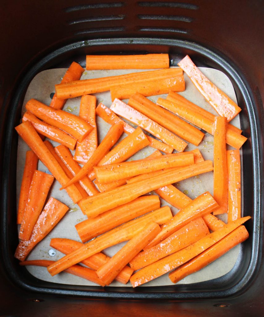 Uncooked carrots in air fryer basket.