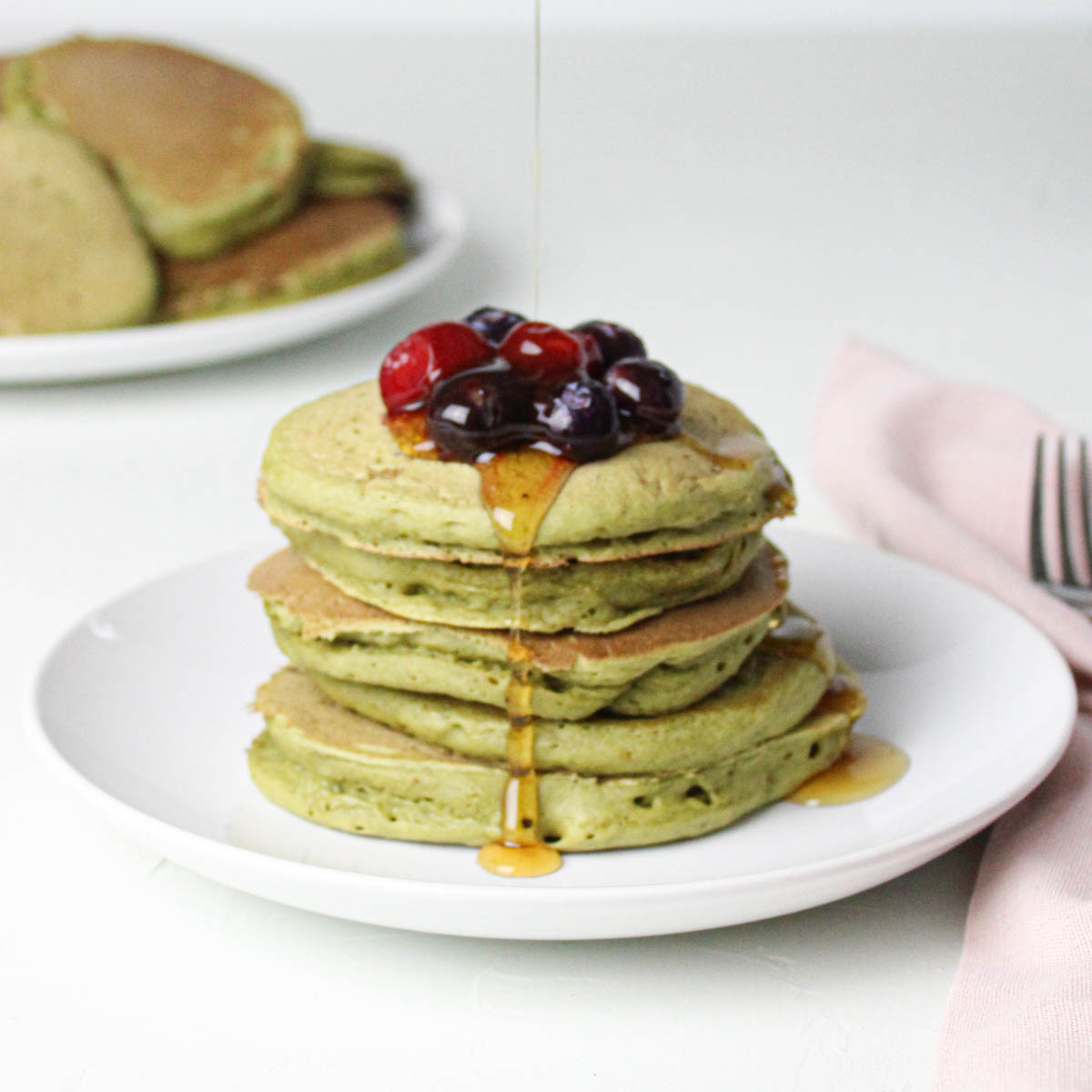 stack of matcha pancakes with berries on top.