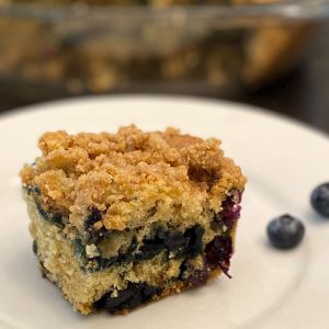 Piece of berry coffee cake with blueberries on a plate.