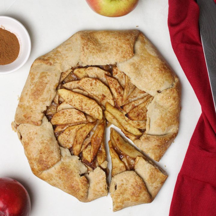 Apple galette with a slice cut out with apples and a red napkin.